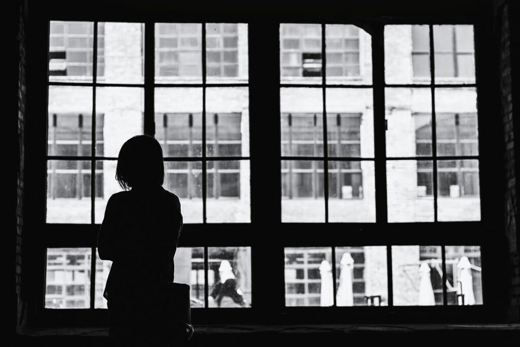 A silhouetted figure looks out from a window